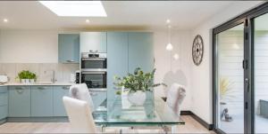 a kitchen with a glass table and white chairs at Little Seven Oaks in Langley +13 photos