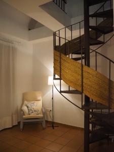 a living room with a chair and a spiral staircase at Sendero de la Subbetica - Apartamentos Turisticos en Zuheros - Holiday Home in Zuheros