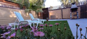 Tres sillas blancas sentadas en un jardín con flores en Casa Soleada en Arona