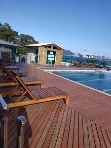 um deque com bancos de madeira junto a uma piscina em LOFT com garagem e piscina Prédio frente MAR em Balneário Camboriú