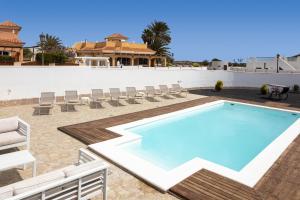 a swimming pool on a patio with chairs and a house at Luxury Villa Nieve in Caleta De Fuste