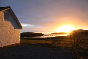 einen Sonnenuntergang über einem Wasserkörper mit einem Gebäude in der Unterkunft The Loft at Strathardle - Lochside Apartment, Isle of Skye in Dunvegan