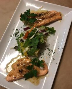 a white plate with two pieces of fish and a salad at Landgasthof Fegetasch in Neukirchen