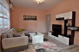a living room with a couch and a tv at Апартамент Фреш in Velingrad