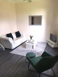 グラスゴーにあるVogue Apartmentsのリビングルーム(白いソファ、テレビ付)