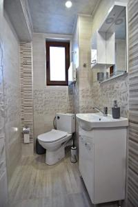 a bathroom with a white toilet and a sink at Апартамент Фреш in Velingrad +7 photos