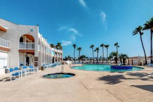 a resort with a pool and chairs and palm trees at Long Island Village Unit 347 in Port Isabel