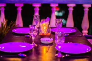 巴加的住宿－Baga Fantacia Beach Inn，一张桌子,上面有紫色盘子和玻璃杯