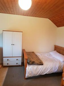 a bedroom with a bed with a dresser and a cabinet at Amazingly quiet and peaceful studio getaway. in Woodhall Spa