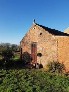 a brick building with a door in a field at Amazingly quiet and peaceful studio getaway. in Woodhall Spa