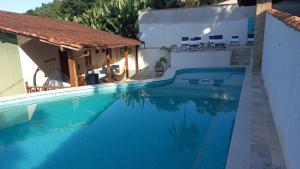 a swimming pool next to a white building with a house at Pousada dos Navegantes in Paraty