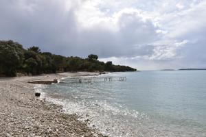 una playa con una orilla rocosa con árboles y agua en Mobile Homes Istria - Brioni Pula, en Pula