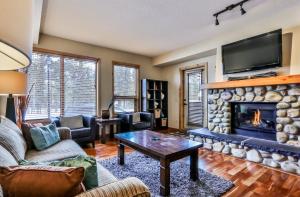 a living room with a fireplace and a tv at Rundle Cliffs Lodge by Spring Creek Vacations in Canmore