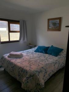 um quarto com uma cama com almofadas azuis e uma janela em Casa Los Canelos em Ushuaia