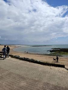 un groupe de personnes marchant sur une plage avec un chien dans l'établissement Maison de pêcheur à 2 pas de la mer (200m), à Bretignolles-sur-Mer