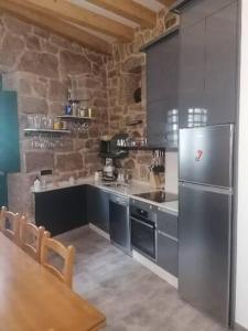 a kitchen with a stainless steel refrigerator and a table at Casiña da Madalena in Ribadavia