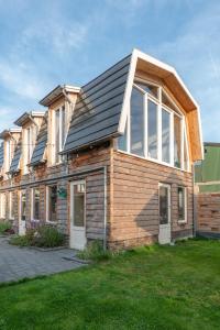 una casa de madera con paneles solares encima en klein polderhuis - bollenschuur, en Roelofarendsveen