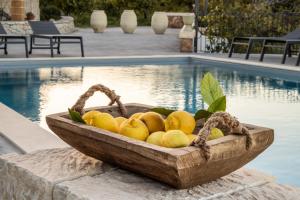 eine hölzerne Schale mit Zitronen neben einem Pool in der Unterkunft Masseria Bio - Agriturismo Villa Grazia in Avola