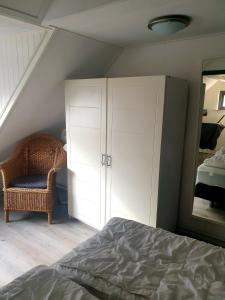 een slaapkamer met een bed, een spiegel en een stoel bij Beach-house27 in Egmond aan Zee