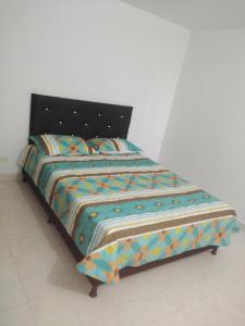 a bed with a colorful comforter in a room at Arriendo hermoso y amplio apartamento amoblado y con piscina, frente a la estación Niquia y al centro comercial puerta del norte. in Bello