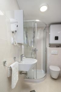 a bathroom with a sink and a shower and a toilet at Apartments Zicara in Dubrovnik