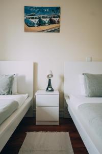 um quarto com 2 camas e uma mesa de cabeceira com um candeeiro em Green Coast Surf House em Espinho