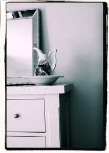 a mirror on a white dresser with a bowl on it at Cozy & Remote Hideaway Gintys Cottage in Ross Port