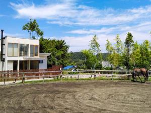 un cheval debout devant une clôture avec une maison dans l'établissement Forest Villa Nanso no Oka - Vacation STAY 39406v, à Minamiboso