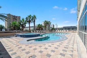 a swimming pool with palm trees and a building at Crystal Tower 1408 - Lazy River, Beachfront pool, Amazing Views, New Upgrades!! in Gulf Shores