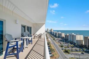 a balcony with chairs and tables and a view of the ocean at Crystal Tower 1408 - Lazy River, Beachfront pool, Amazing Views, New Upgrades!! in Gulf Shores