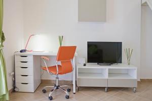 una silla naranja junto a un escritorio con TV en Appartamento Reginella, en Nápoles