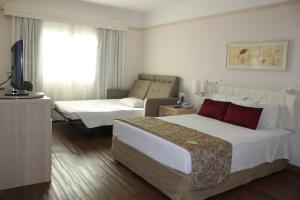 a hotel room with two beds and a television at Comfort Suites Londrina in Londrina