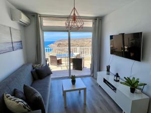 a living room with a couch and a large window at Canarias Sunshine Amadores in Amadores