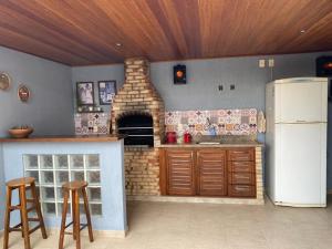 a kitchen with a brick oven and two bar stools at COMFORT DUPLEX in Rio das Ostras