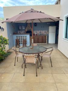 een tafel en stoelen met een parasol op een patio bij COMFORT DUPLEX in Rio das Ostras