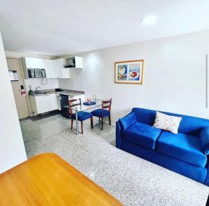 uma sala de estar com um sofá azul e uma cozinha em Apê Beira Mar Meireles Com café da manhã em Fortaleza