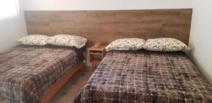 a bedroom with two beds and a night stand with a table at Cabaña La Camelia in Creel
