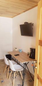 a wooden table with chairs and a television on a wall at Cabaña La Camelia in Creel