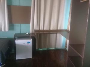 Cette chambre comprend un petit réfrigérateur et un rideau. dans l'établissement Vereda Tropical Piauí, à Luis Correia