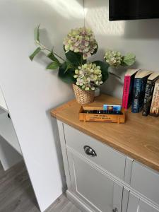 a shelf with flowers and books on top of a cabinet at Lytham Sea Salt Lodge in Lytham St Annes