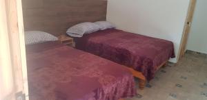 two beds in a small room with purple sheets at Cabaña La Camelia in Creel