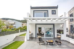 a white house with a patio with two chairs and a table at JOY C Deluxe in Iraklitsa
