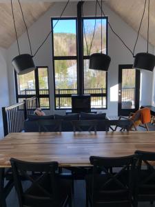 a large room with a table and chairs and windows at Chalet Snocamp in LʼAnse-Saint-Jean