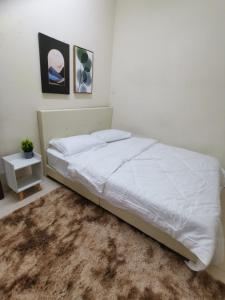 1 dormitorio con cama blanca y alfombra en HomestayKu @Bachok en Bachok