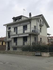 ein großes weißes Gebäude mit Balkonen und einem Zaun in der Unterkunft Guest House MICINI in Druento
