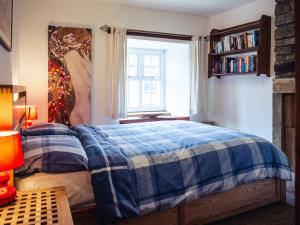 a bedroom with a bed with a blue and white blanket at Bastle House in Haltwhistle