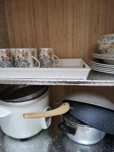 a shelf with cups and a pot and a wooden spoon at HomestayKu @Bachok in Bachok +23 photos