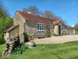 a stone cottage with a bench in a yard at Magpie Cottage in South Brewham