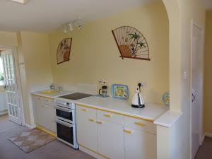 a kitchen with white cabinets and a stove at Magpie Cottage in South Brewham