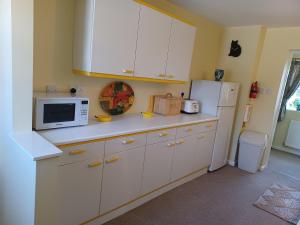 a kitchen with white cabinets and a white refrigerator at Magpie Cottage in South Brewham